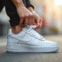 Main d'une femme nouant des Nike Air Force One blanches en extérieur