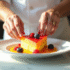 Chef dressant un dessert de fruits en forme de V sur une assiette blanche