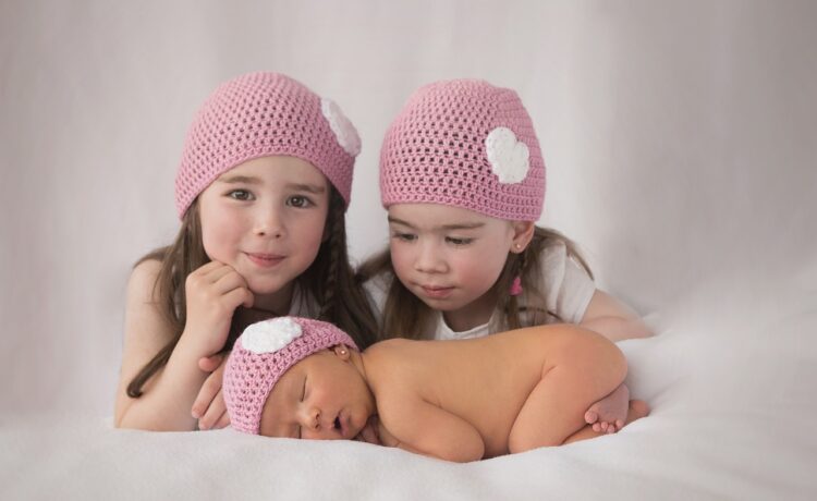 Deux jeunes soeurs avec leur petit frère nouveau né