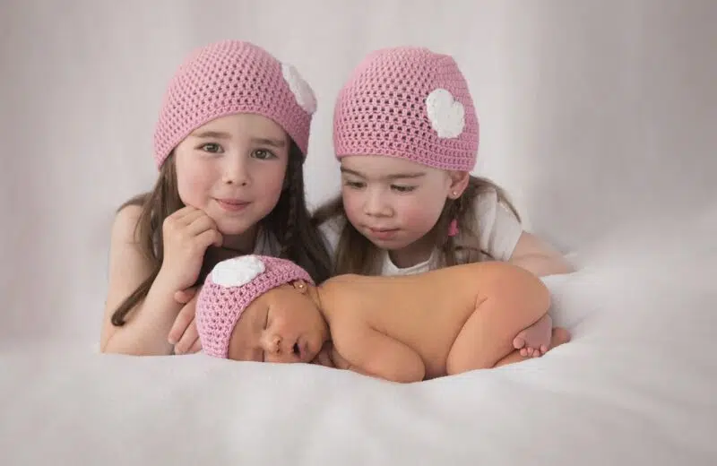Deux jeunes soeurs avec leur petit frère nouveau né