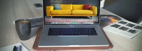 turned on MacBook Pro beside gray mug